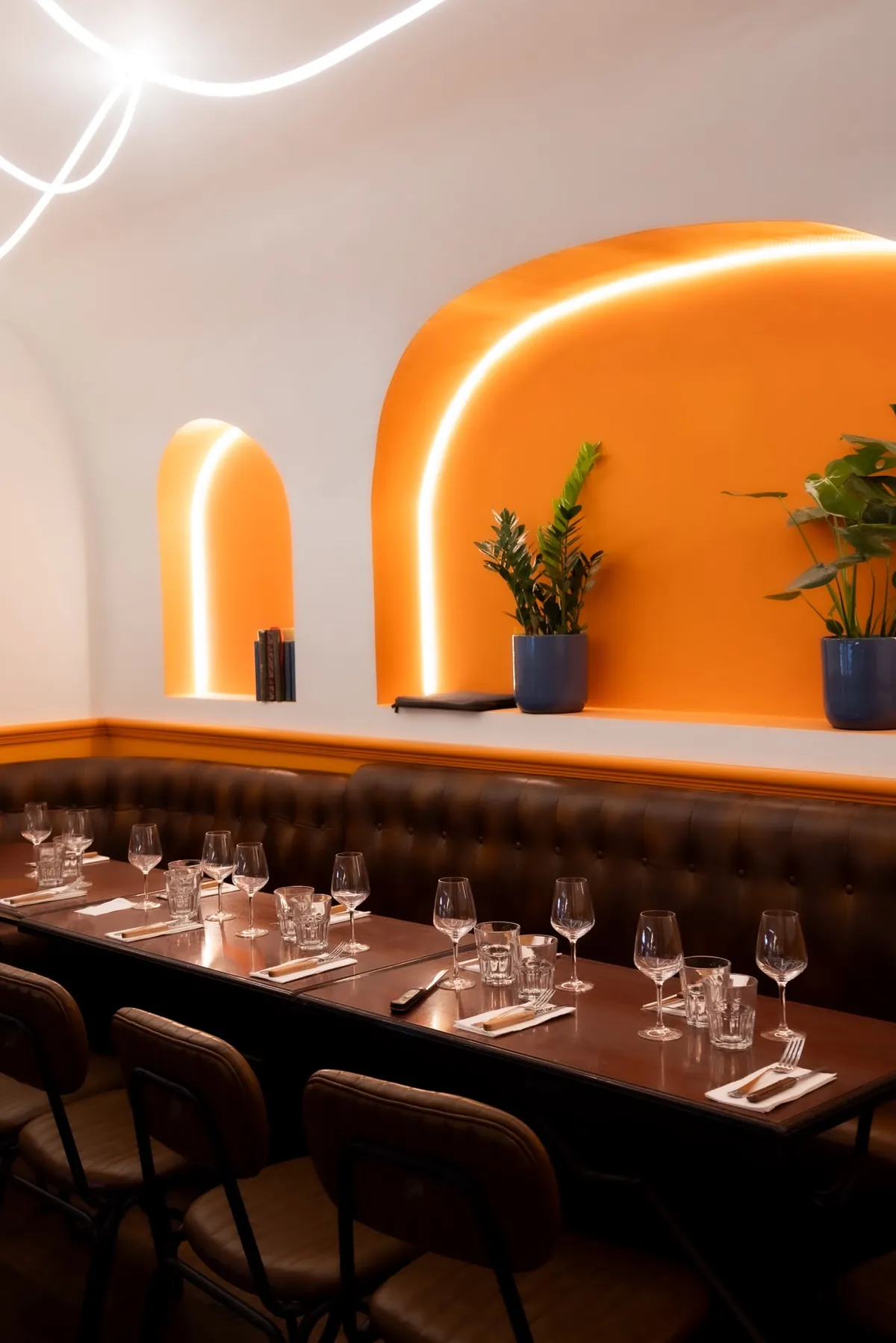 La salle de L’Étincelle et ses arches orange lumineuses, banquette en cuir et tables dressées