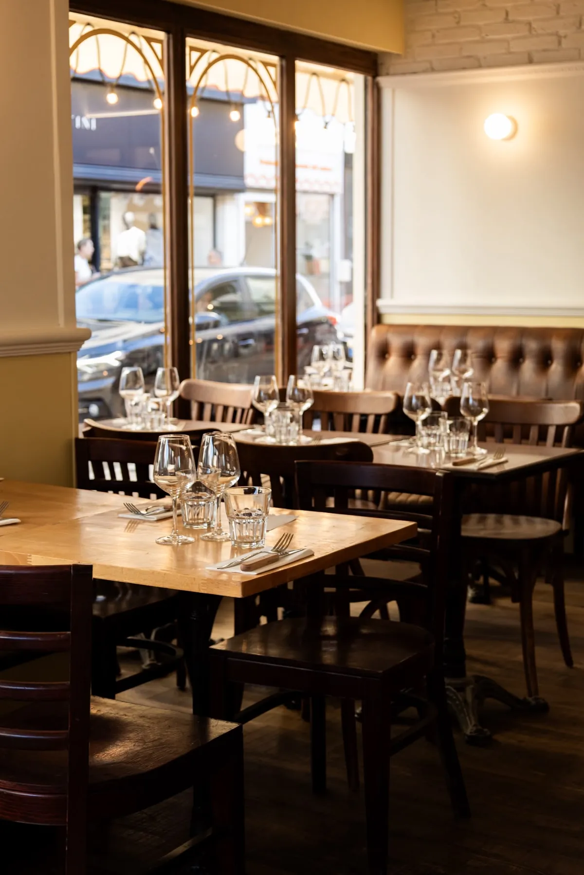 Tables dressées et banquette le long des vitrines de la brasserie L’Étincelle